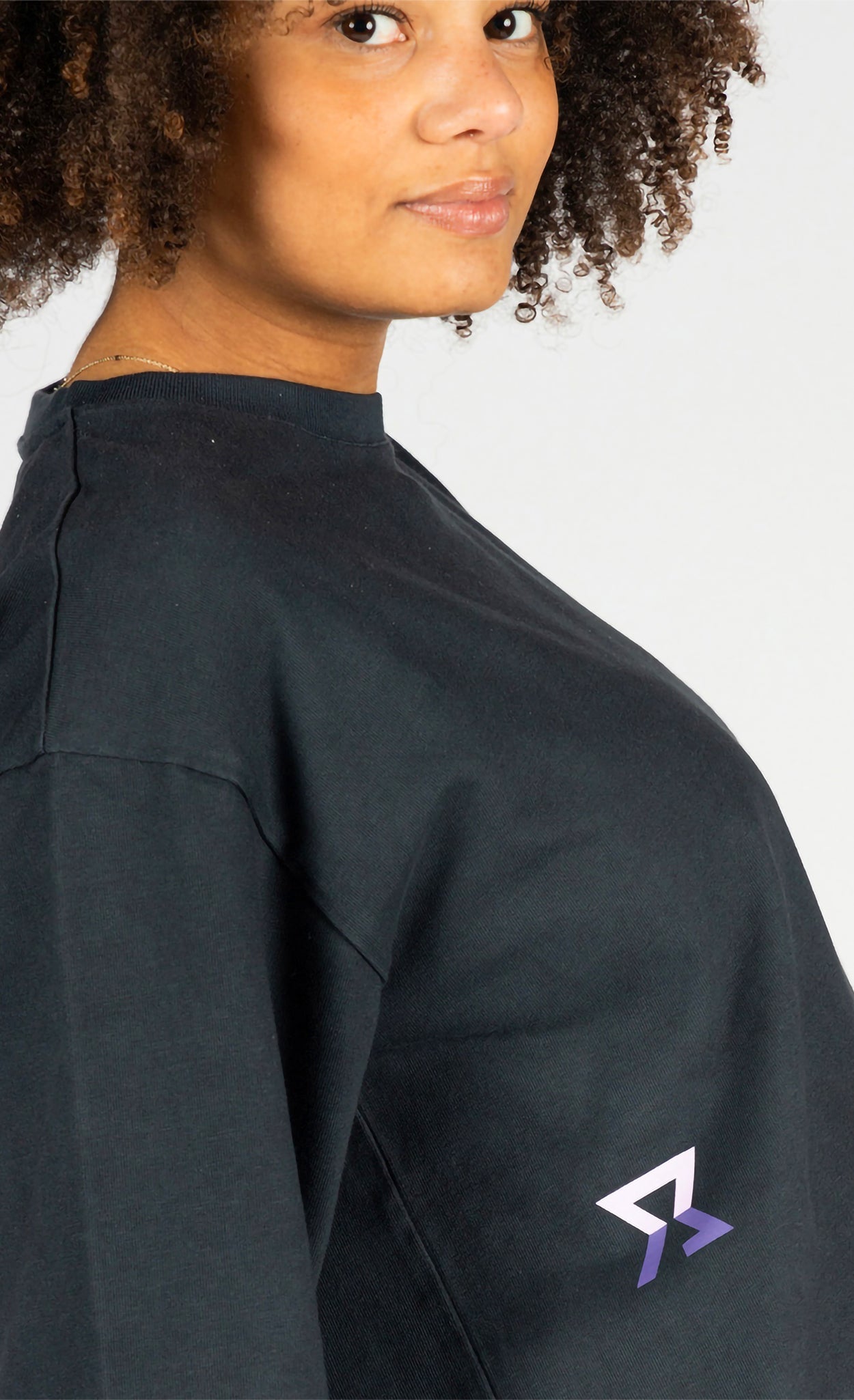 Person wearing a blue polo long sleeve shirt with a side logo on a white background