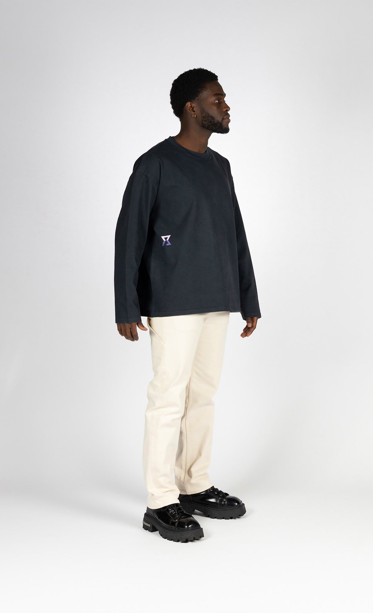 Man wearing a black long-sleeve shirt and beige pants on a white background