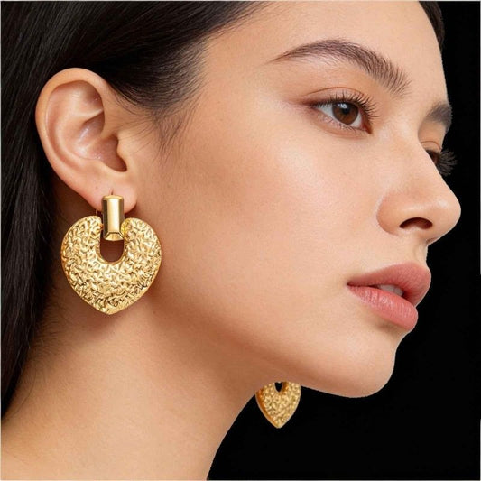 Close-up of a woman wearing gold hoop earrings with a black background