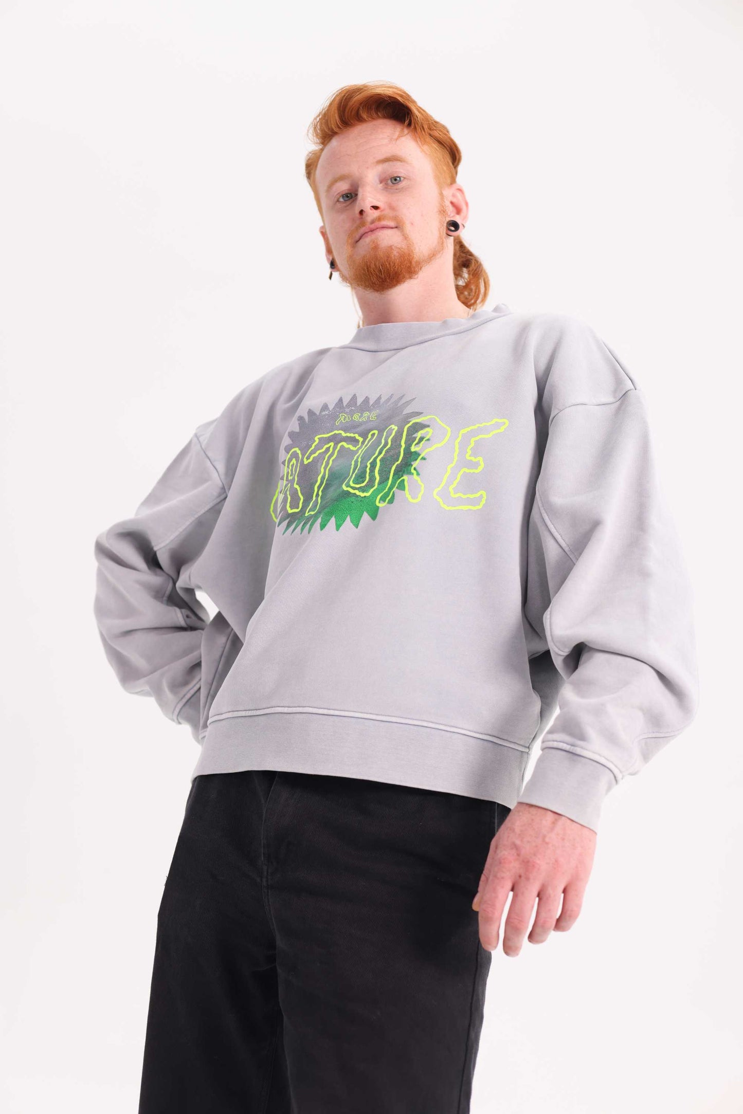 Person wearing a gray sweatshirt with green nature text on a white background