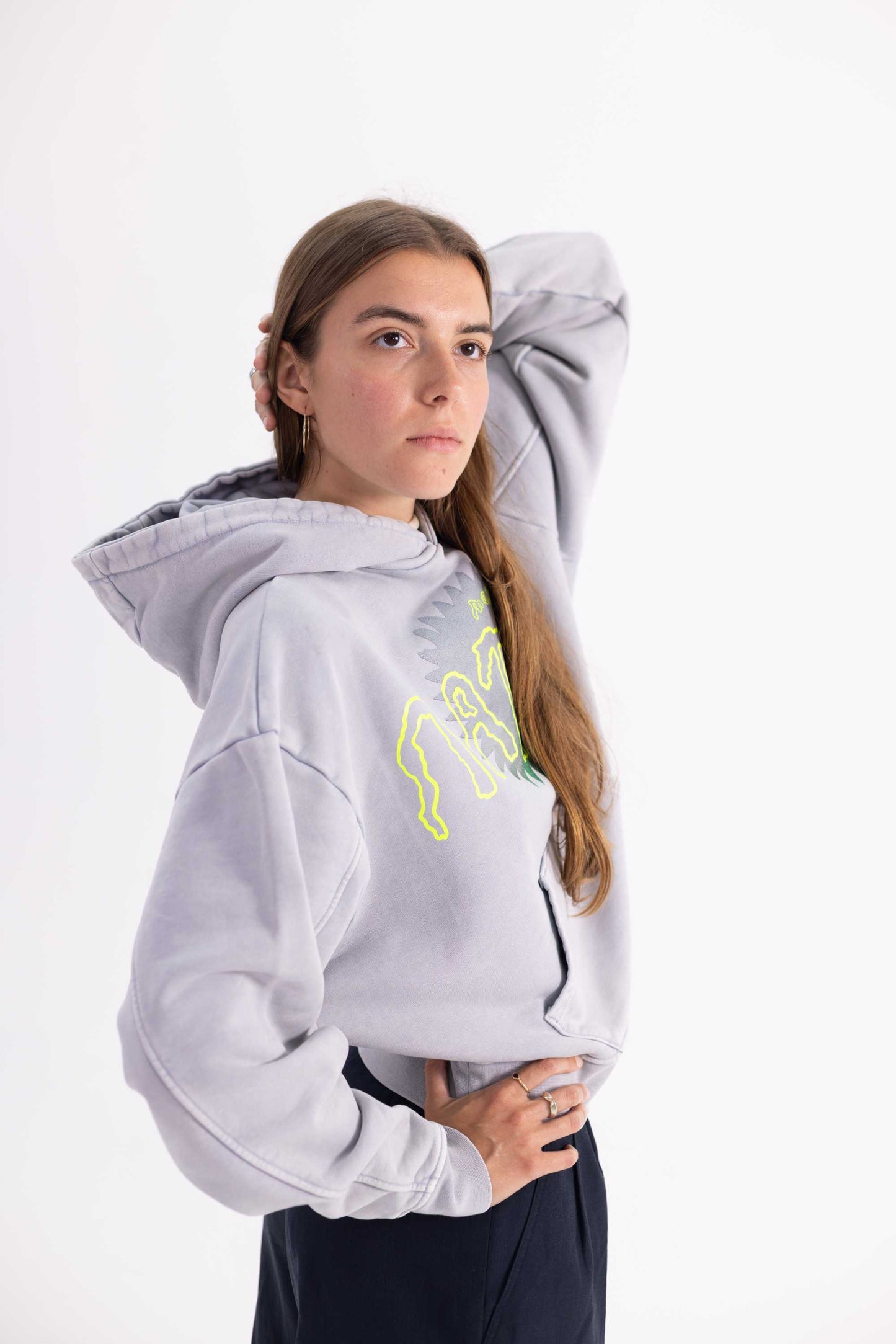 Female model wearing a grey hoodie with a nature logo on a white background