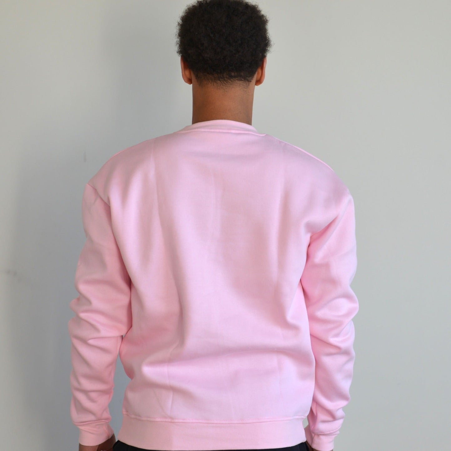 Person wearing a pink sweatshirt against a plain background