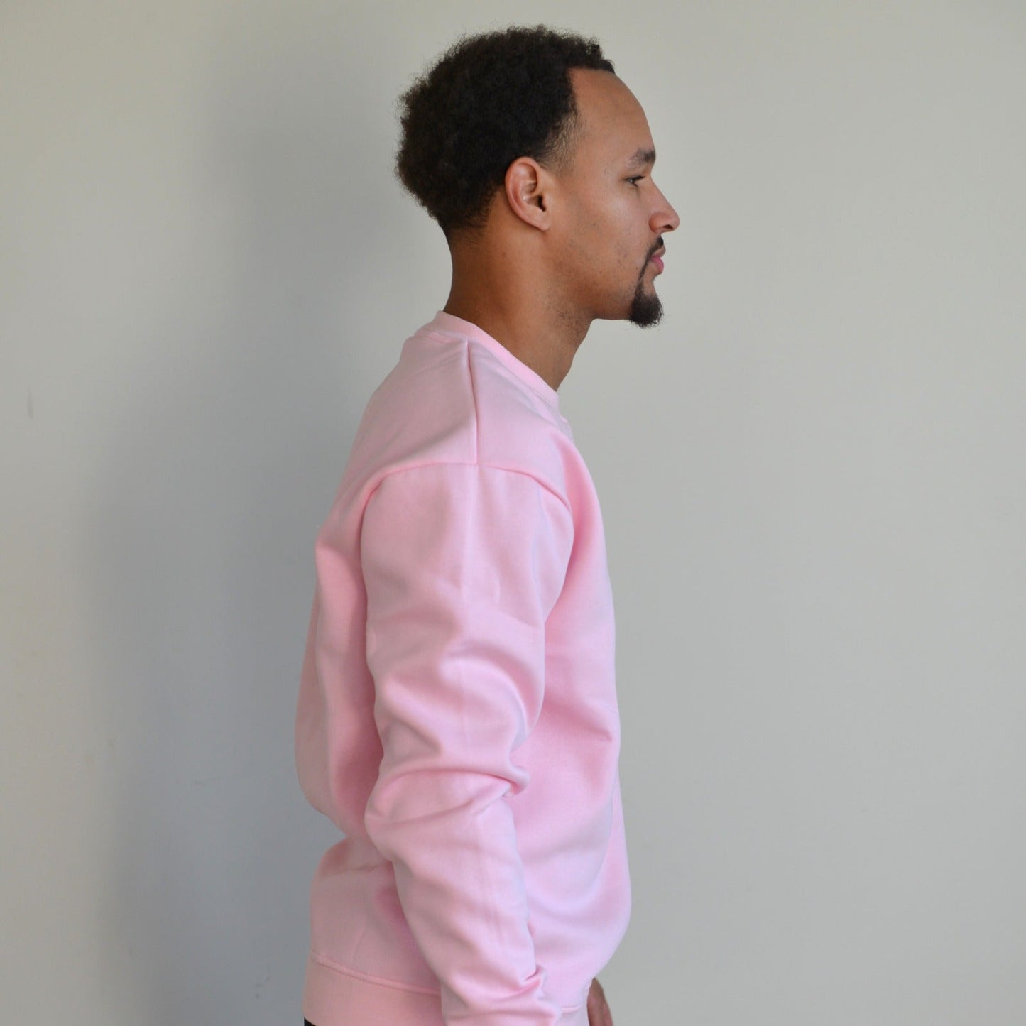 Man wearing a pink sweatshirt against a plain background