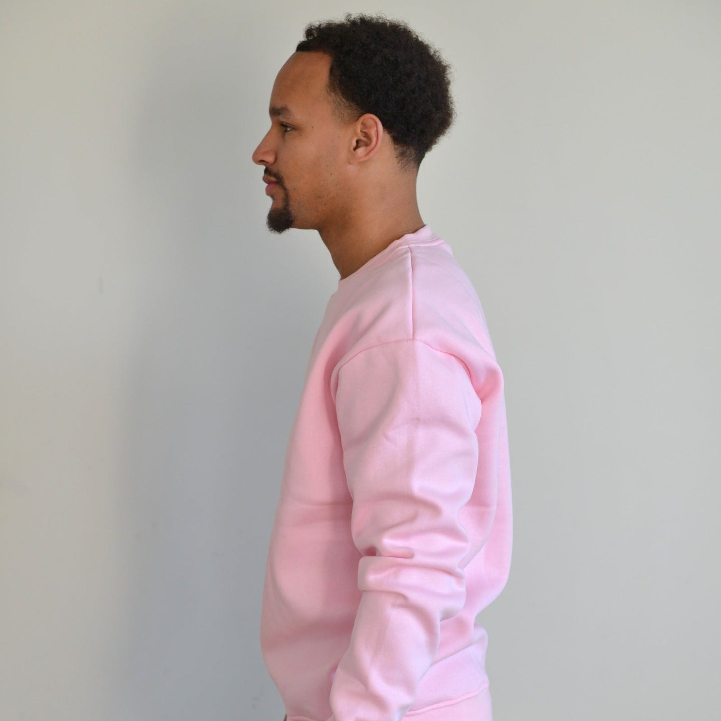 Person wearing a pink sweatshirt against a plain background