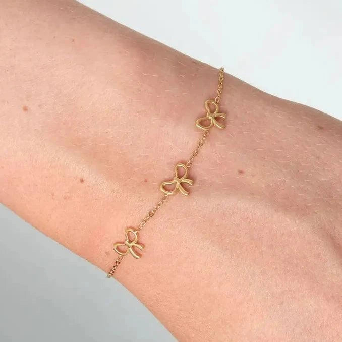 Three Charm Bow Gold bracelet  on a woman's wrist- Gbaje Jewelry