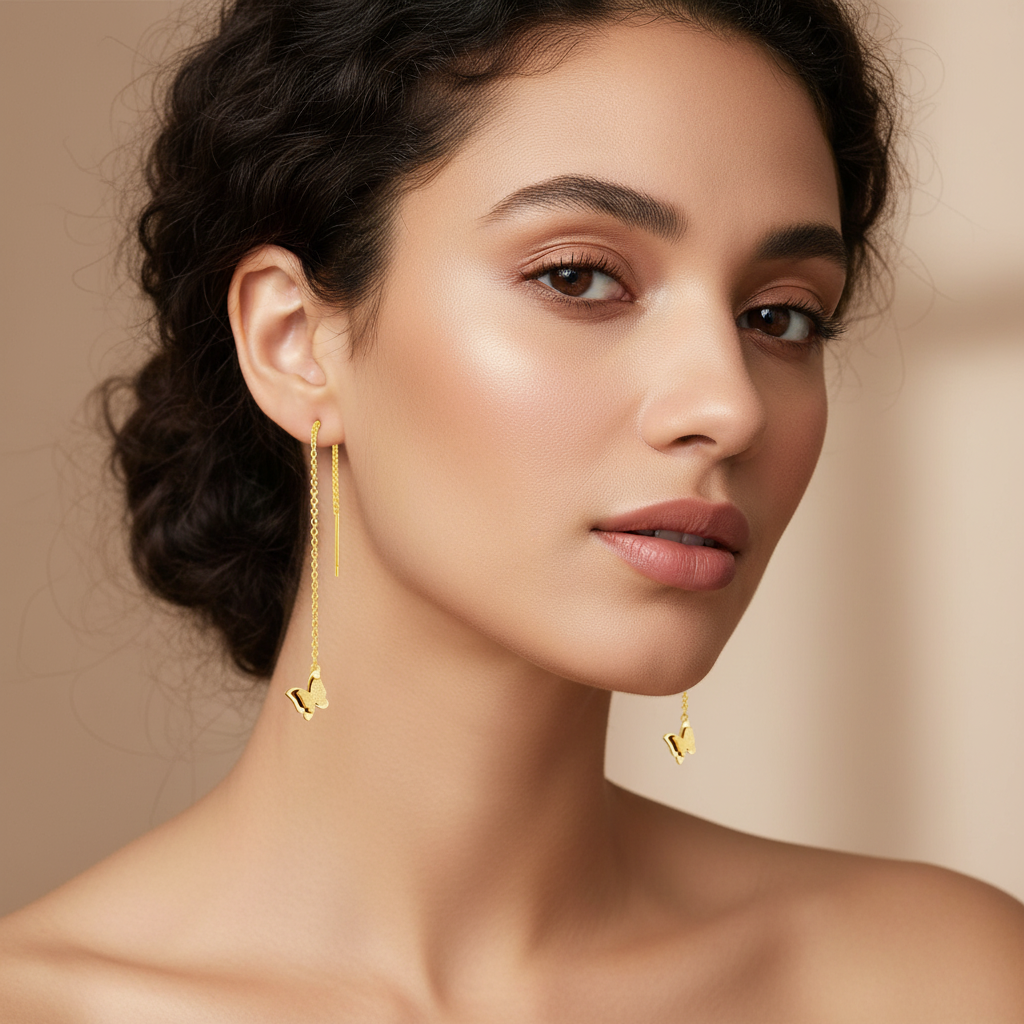 Woman wearing gold threader earrings against a beige background | Gbaje Jewelry 