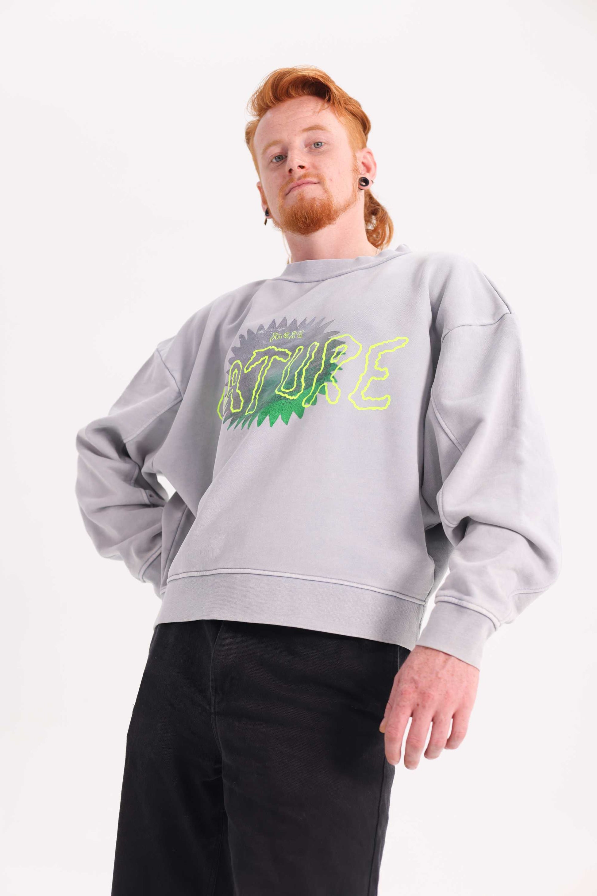 Person wearing a gray sweatshirt with green nature text on a white background