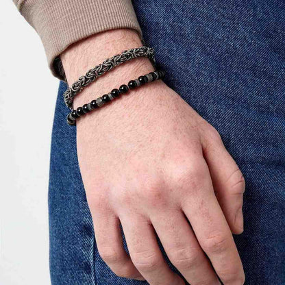 Hand wearing two bracelets on a plain background