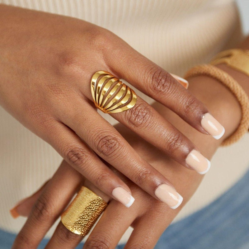 Close-up of a hand wearing two gold rings with a blurred background