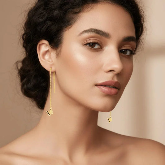 Woman wearing gold earrings against a beige background