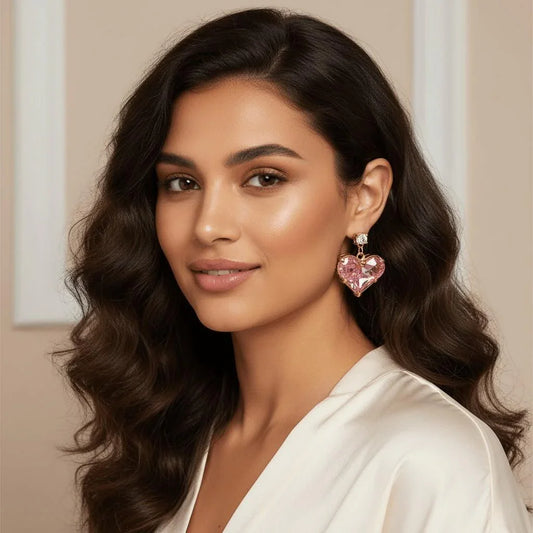 Woman wearing heart-shaped pink earrings with a neutral background