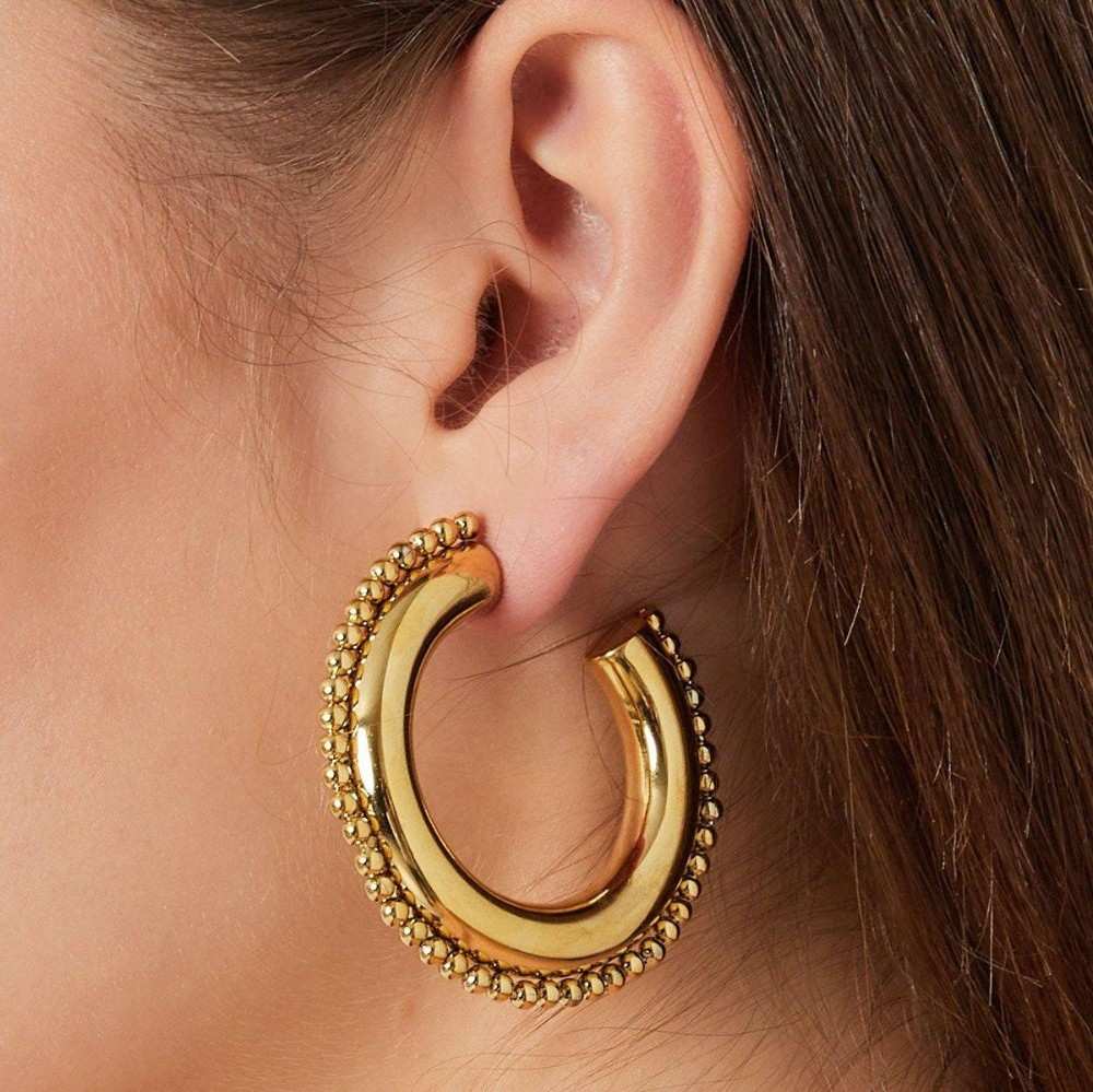 Gold hoop earring worn by a person with brown hair.