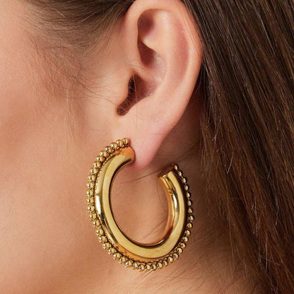 Gold hoop earring worn by a person with brown hair.