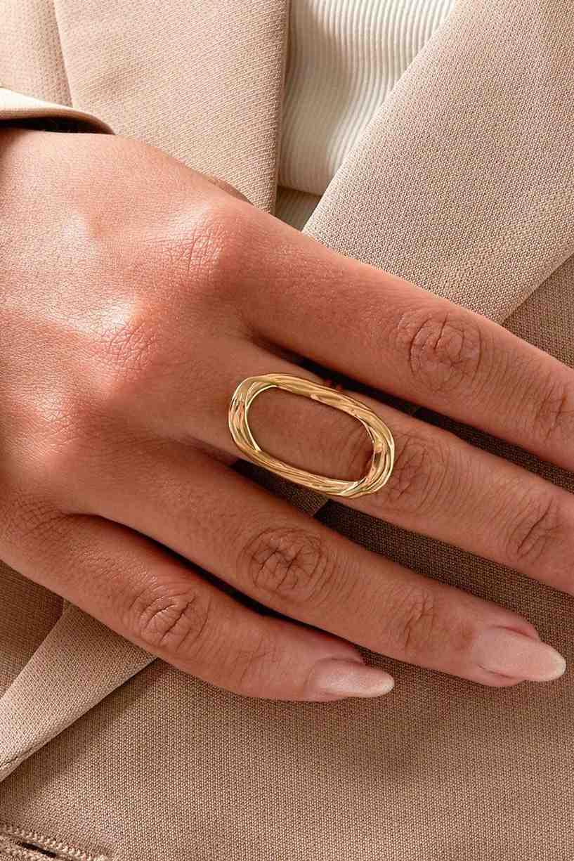 Gold ring on a person's finger with a neutral background