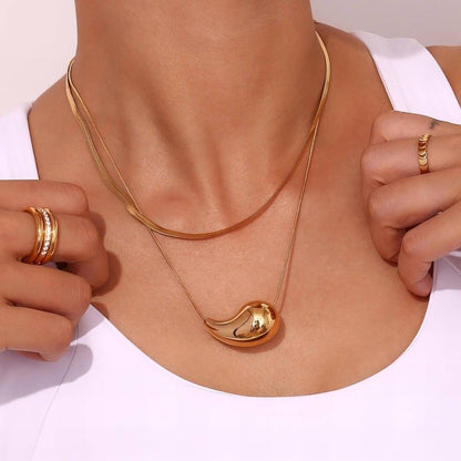 Gold necklace with a pendant worn by a person on a white background